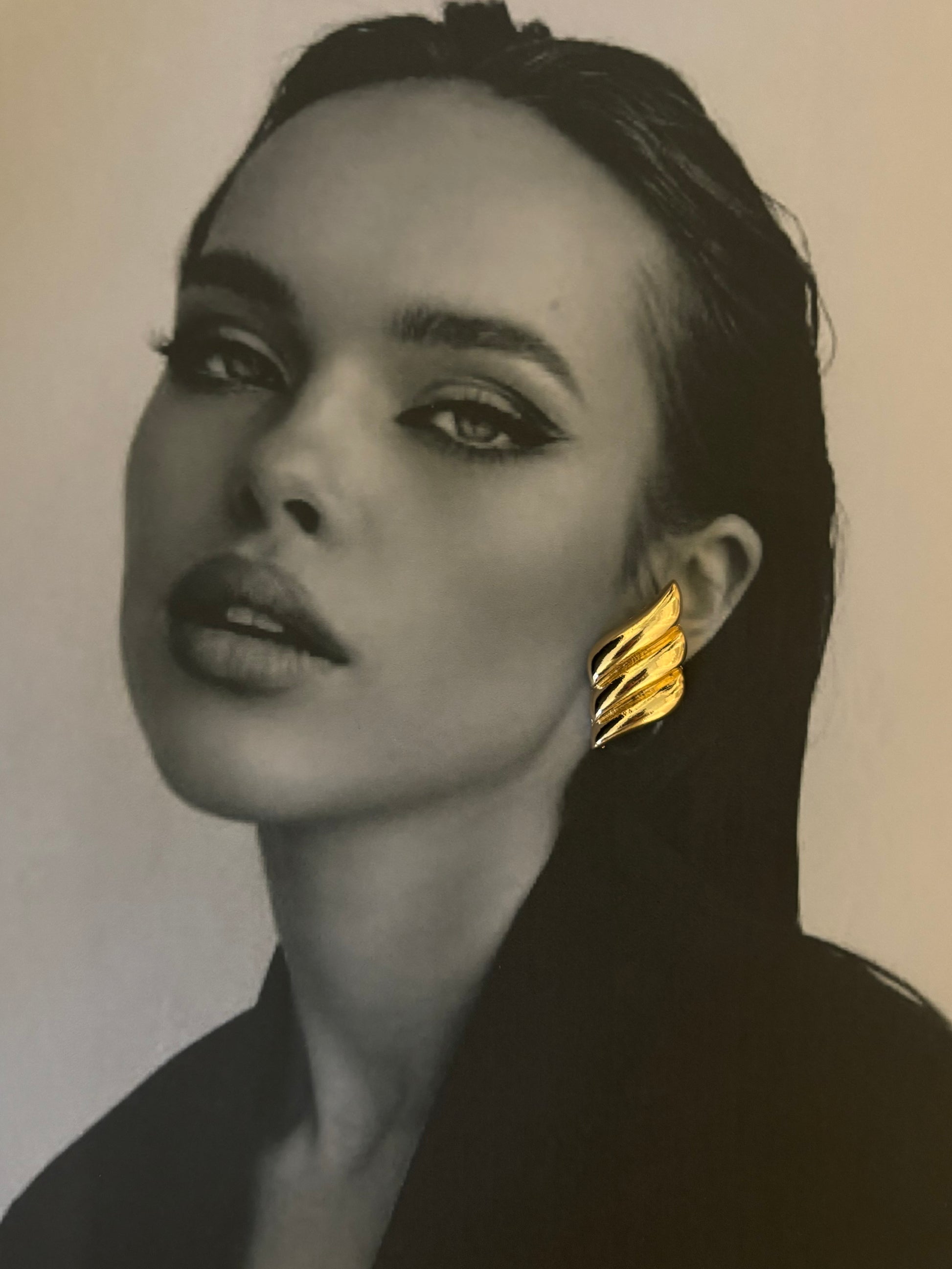 Striking portrait featuring a model wearing the Paloma Earrings by ÈRE, showcasing their glamorous design as eye-catching gold statement earrings.