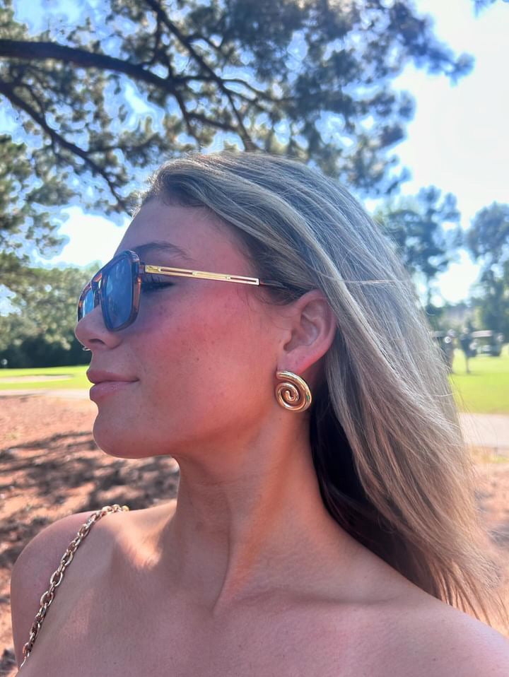 Artistic black-and-white image of a model wearing ÈRE Iris Earrings, illustrating the timeless beauty of these gold statement earrings.