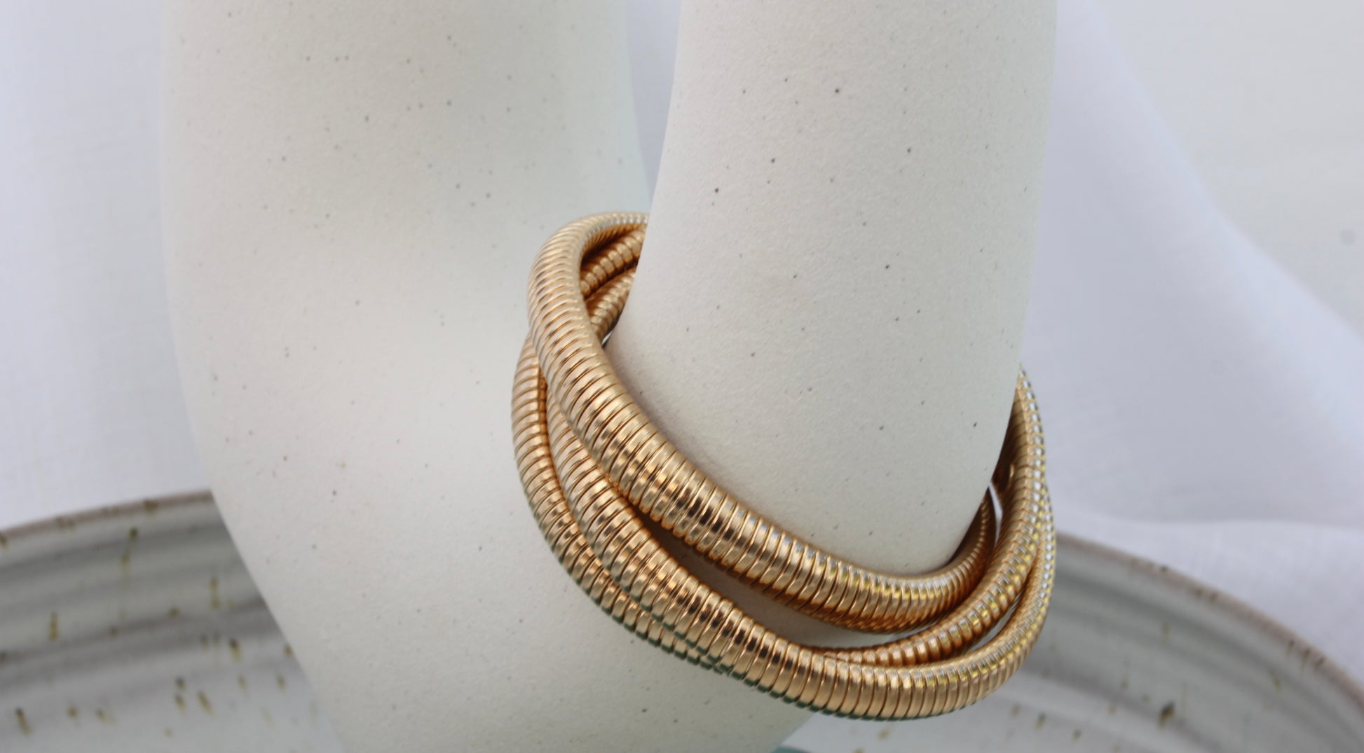 Rowe Bangle by ÈRE elegantly resting on a display piece, the modern gold bangle showcases a chic and sophisticated look.