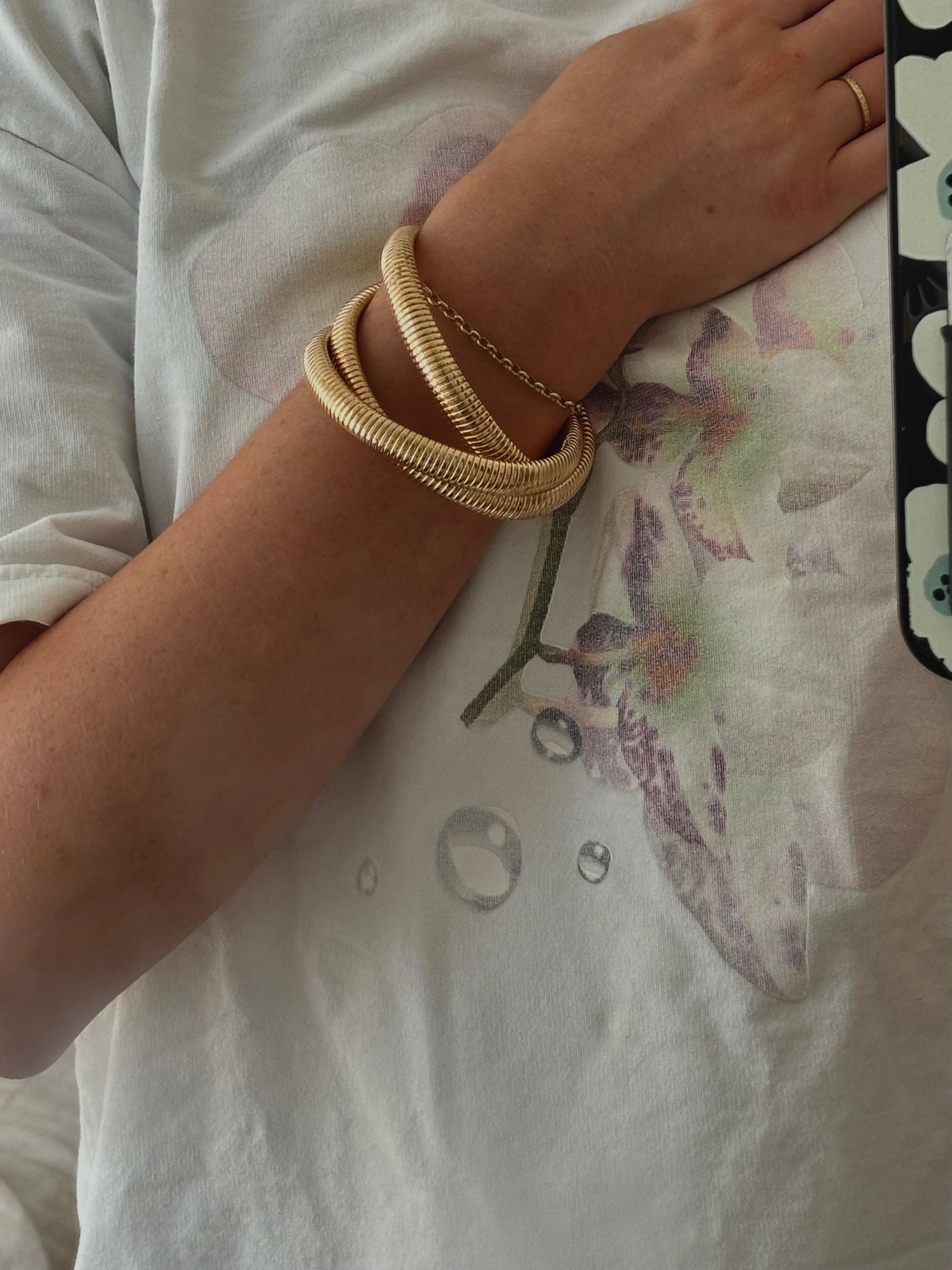 Fashionable Rowe Bangle by ÈRE worn on a model's arm, highlighting the intricate details of the gold bangle in a casual setting.