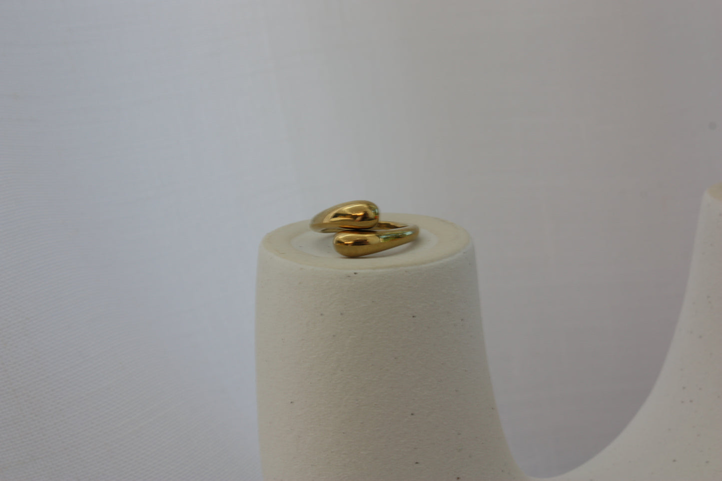 Beautiful adjustable gold ring by ÈRE displayed atop a decorative stand, highlighting its versatile design and luxurious 18K gold plating.