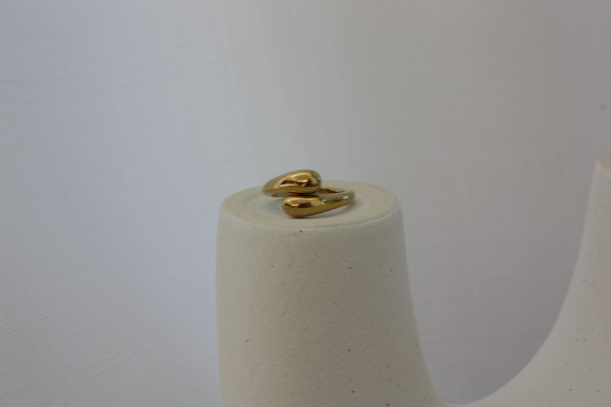 Beautiful adjustable gold ring by ÈRE displayed atop a decorative stand, highlighting its versatile design and luxurious 18K gold plating.