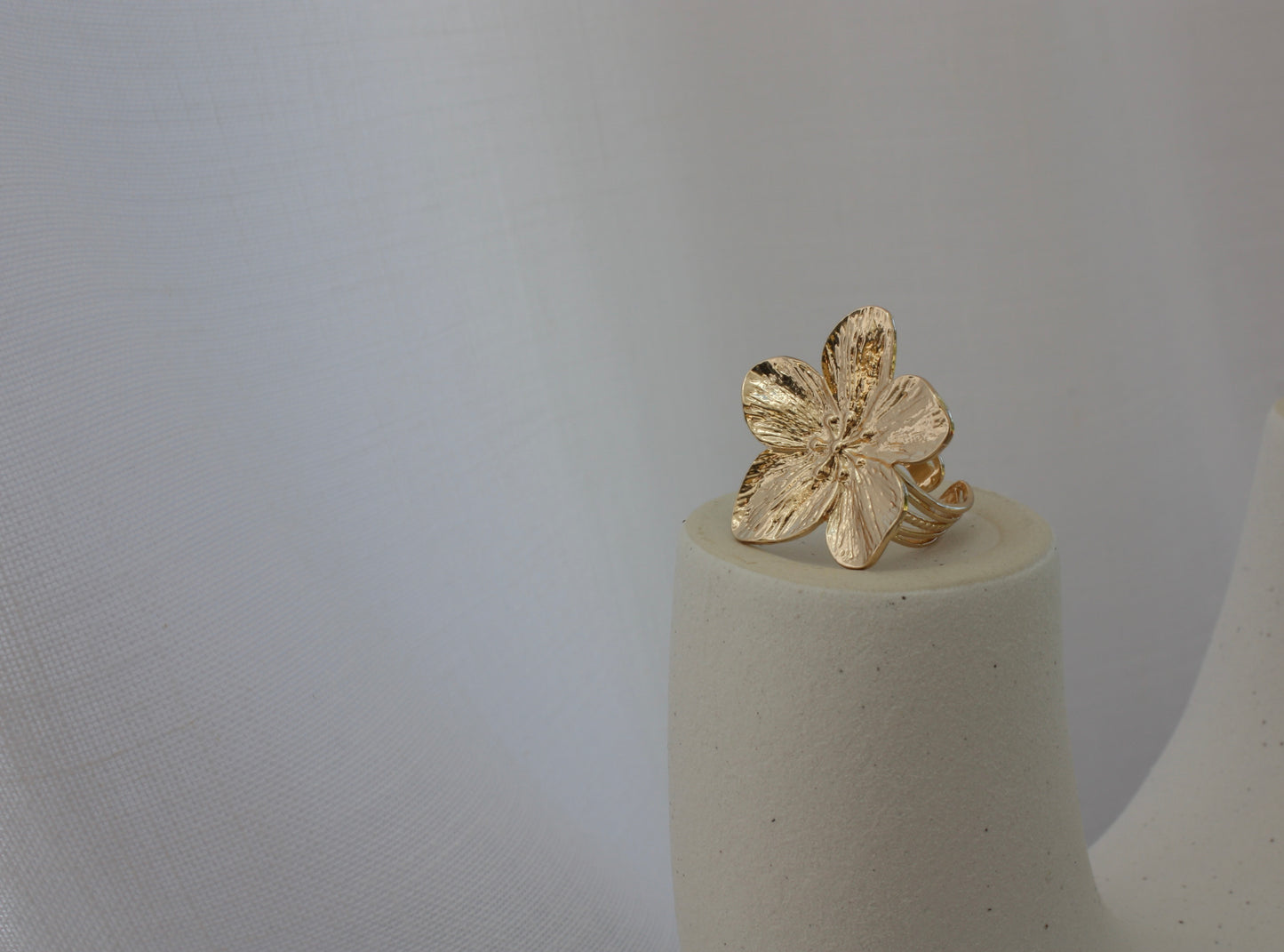 The Fleur Ring displayed artistically on a minimalist pedestal, illustrating its floral design in a stunning presentation by ÈRE, highlighting it as a flower statement ring.