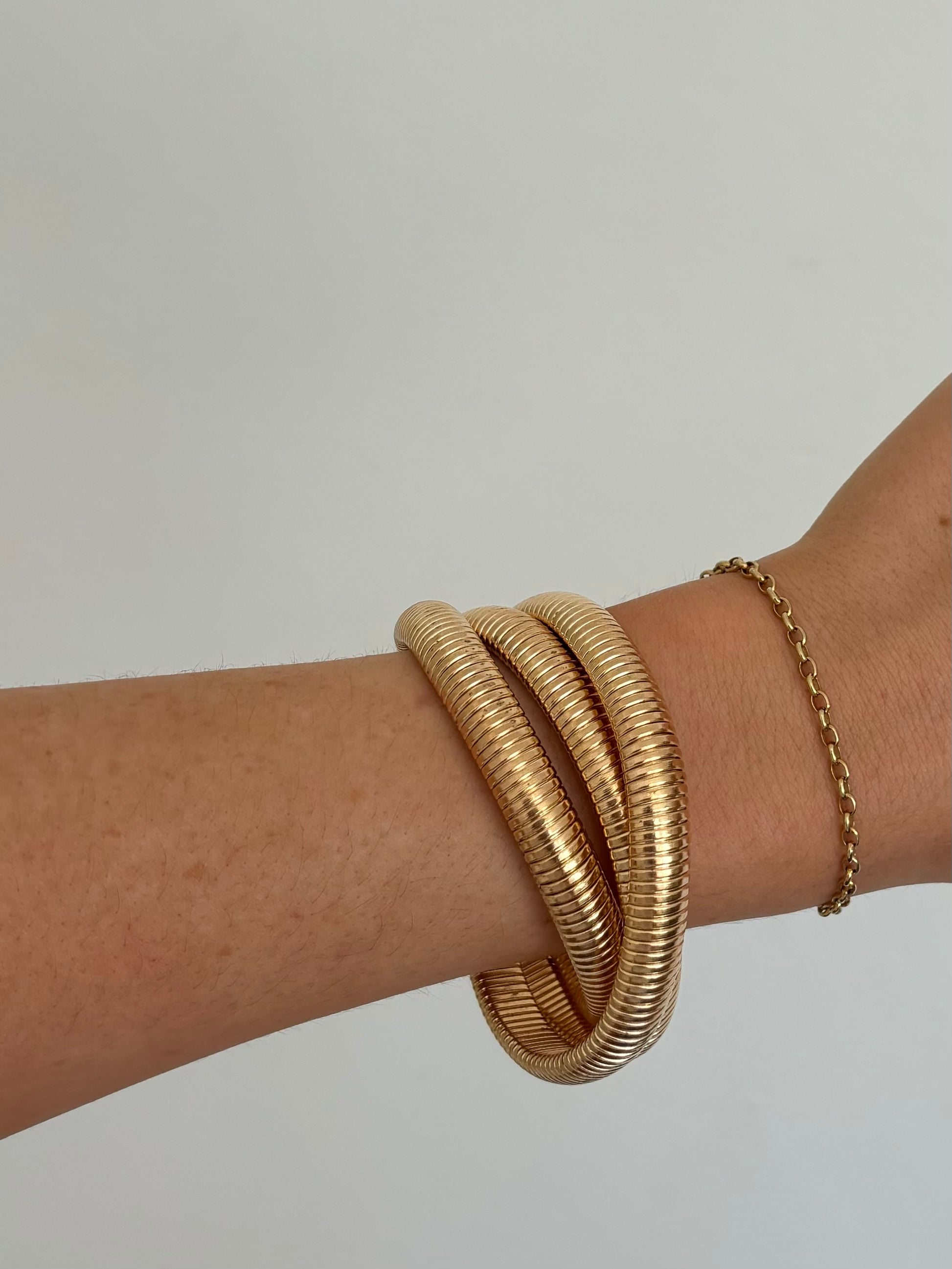 Rowe Bangle by ÈRE adorning a model's wrist, showcasing the eye-catching design of the gold bangle in a relaxed pose.